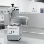 Le coupe-légumes professionnel Robot Coupe CL 40 en action dans une cuisine professionnelle, entouré de légumes frais, ambiance de service intense.